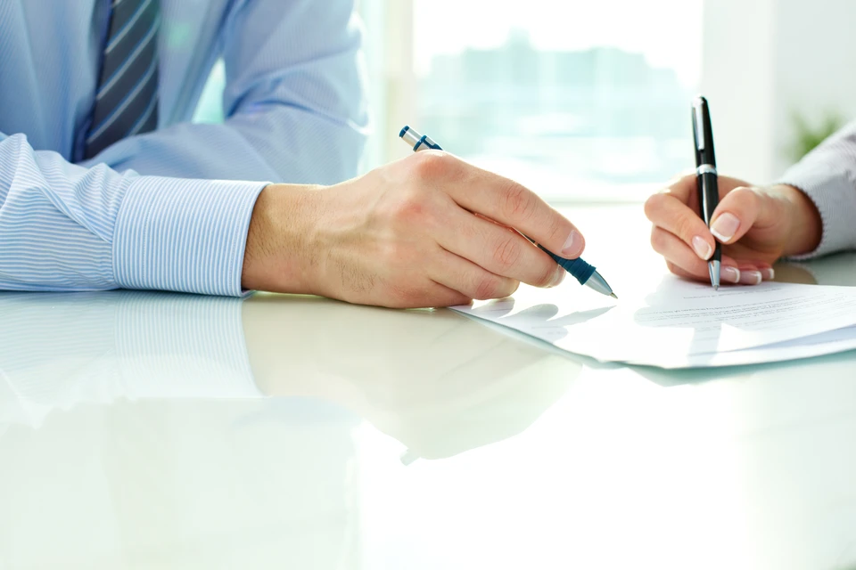 Bureau professionnel avec deux personnes en costume analysant des documents contractuels