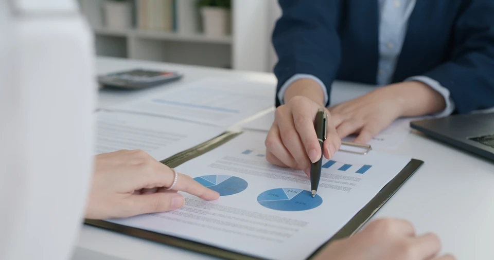 Réunion d'affaires dans un bureau moderne avec deux professionnels analysant des graphiques financiers