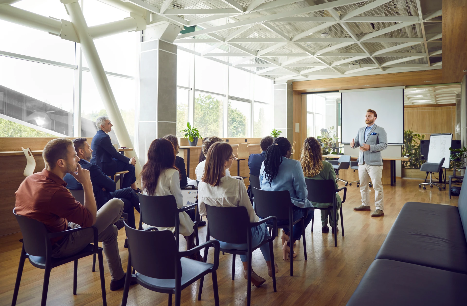 Un formateur en chemise blanche présente devant un tableau blanc à quatre participants assis